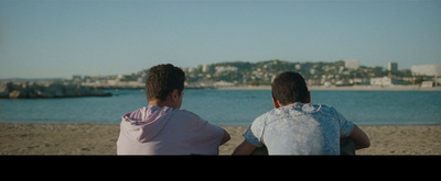 a couple of people sitting on top of a sandy beach