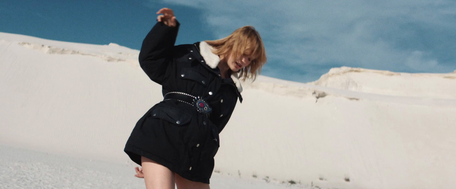 a woman in a black coat is standing in the snow