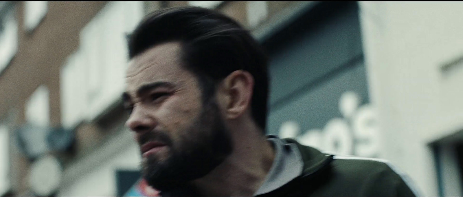 a man with a goatee and a beard standing in front of a building