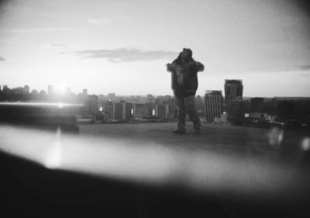 a man standing on top of a roof next to a tall building