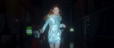 a woman in a shiny blue dress walking in the dark