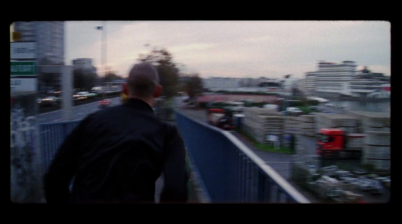 a man standing on top of a bridge next to a parking lot