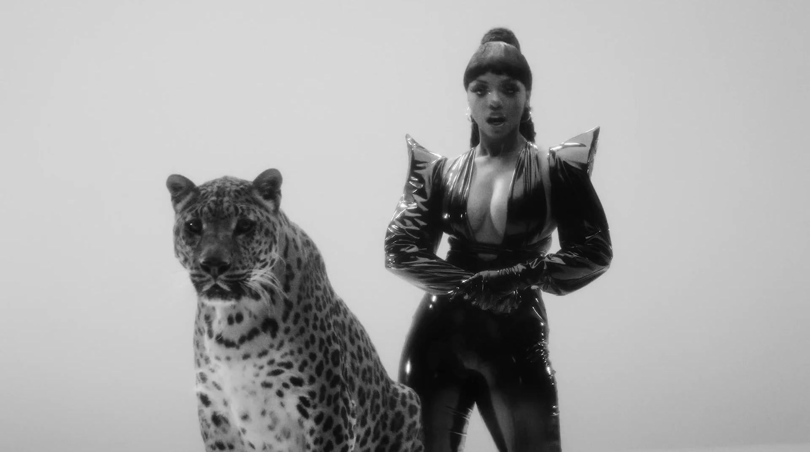 a black and white photo of a woman standing next to a statue of a leopard