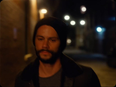 a man with a beard standing on a street at night