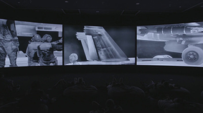 a group of people standing in front of three large screens