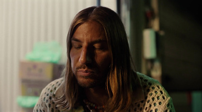 a man with long hair looking down at his cell phone