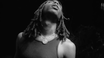 a man with dreadlocks standing in the dark