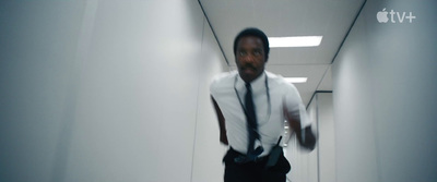 a man in a suit and tie walking down a hallway