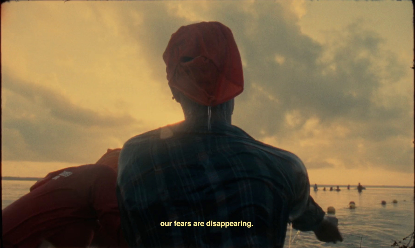 a man in a red hat looking out at the ocean