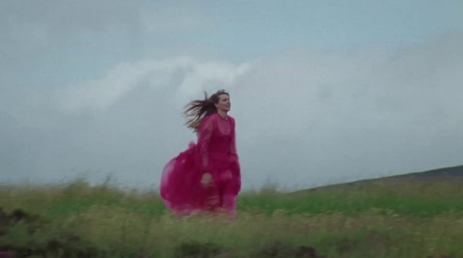 a woman in a pink dress running through a field