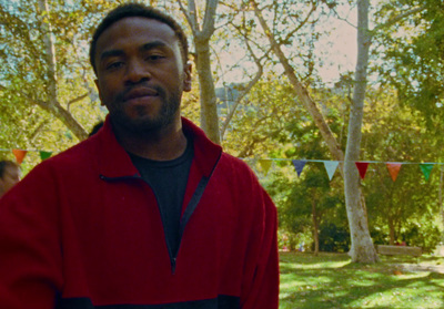 a man in a red jacket standing in a park