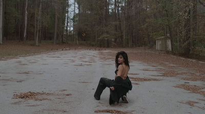 a woman sitting on the ground in the middle of a road