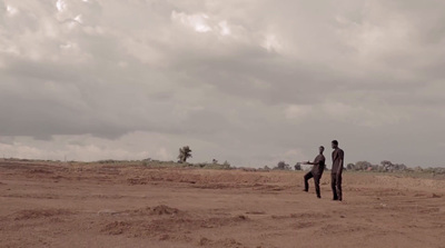 two people standing on a beach flying a kite