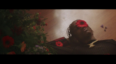 a man laying on the floor with a red flower in his hair