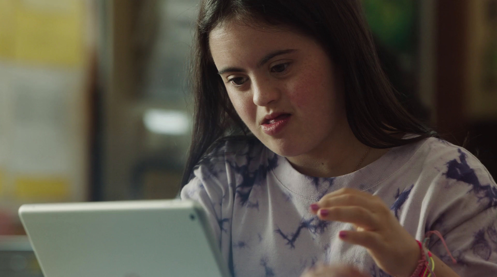 a young girl sitting at a table using a laptop computer