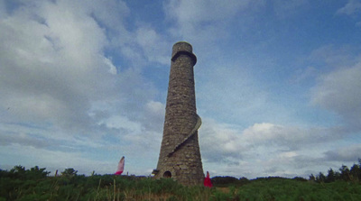 a tall stone tower sitting on top of a lush green field