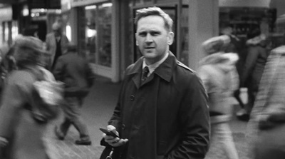 a black and white photo of a man in a trench coat