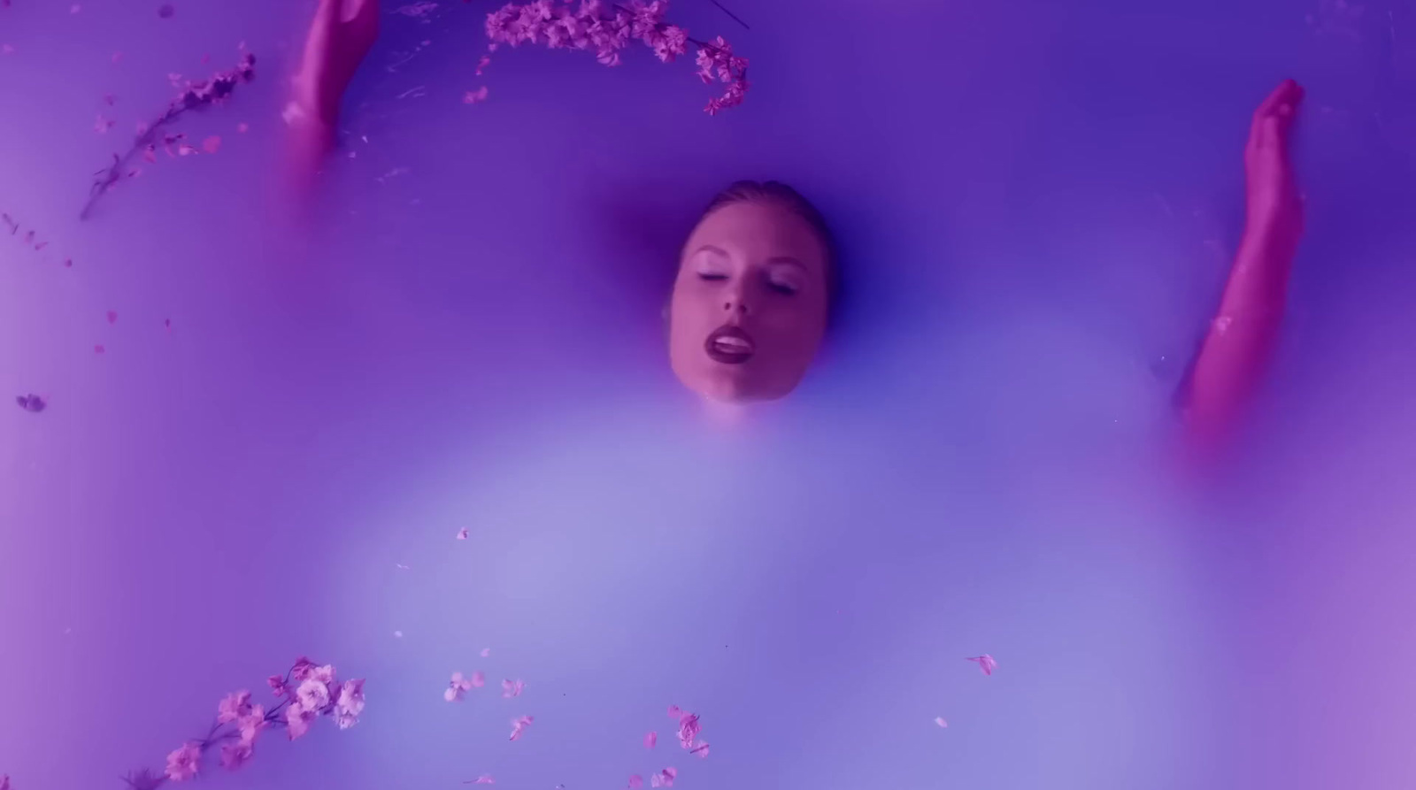 a woman is floating in a purple bubble bath