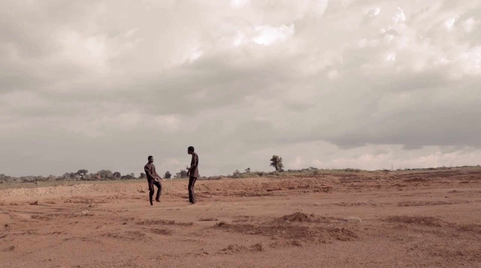 a couple of men standing on top of a sandy field