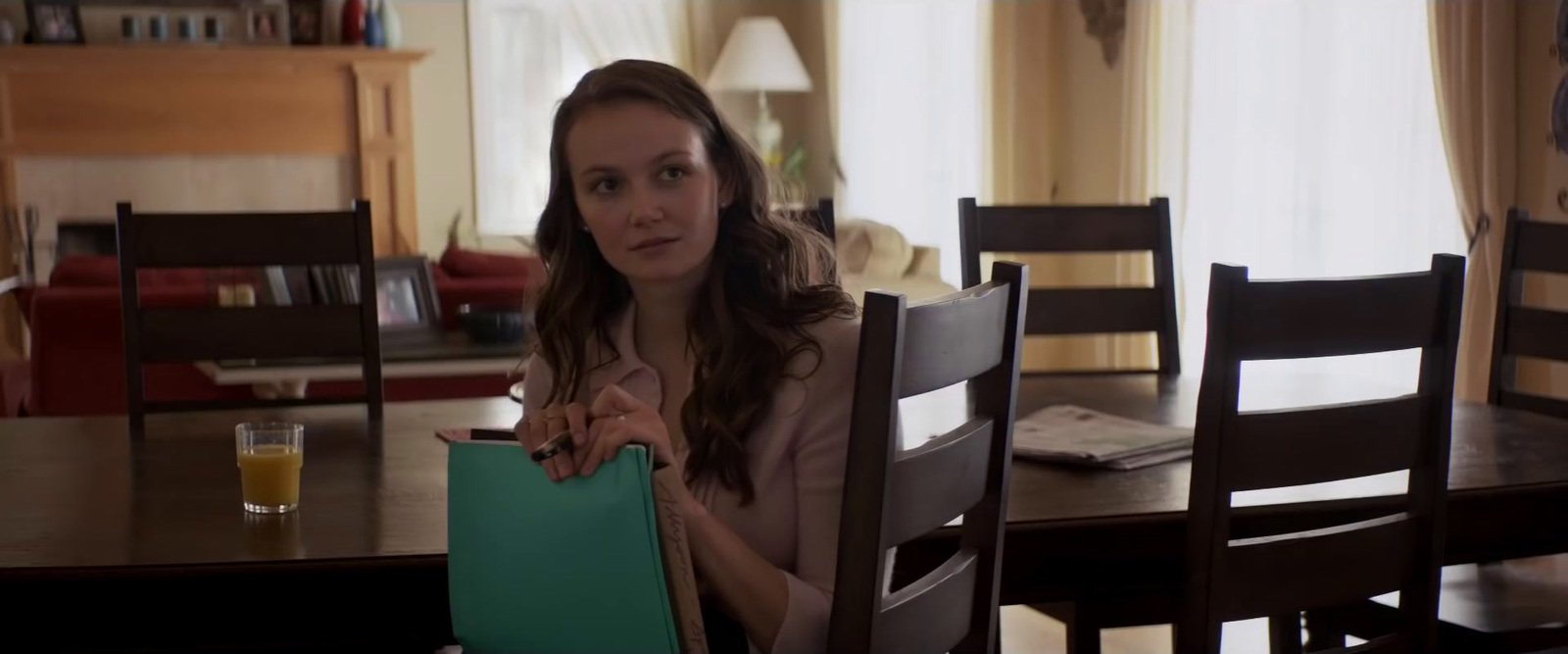 a woman sitting at a table with a green bag