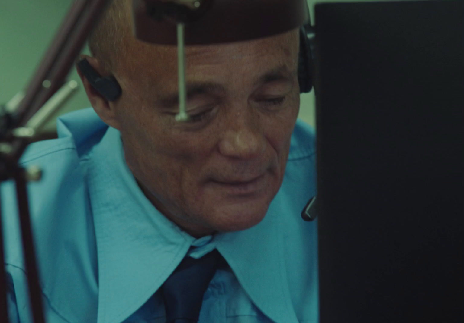 a man in a blue shirt and tie looking at a laptop