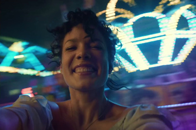 a woman is smiling in front of a carnival ride