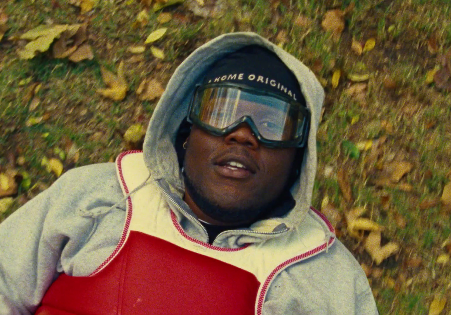 a man wearing goggles and a hoodie laying on the ground