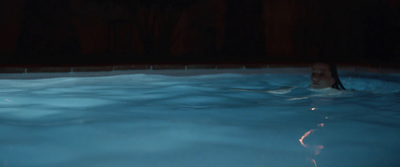 a woman swimming in a pool at night