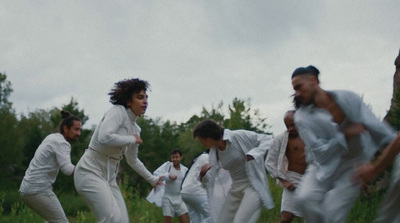 a group of people in white clothes running through a field