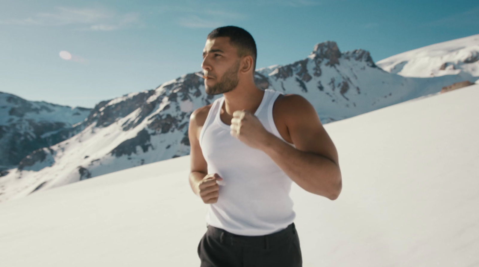 a man in a white tank top is running in the snow