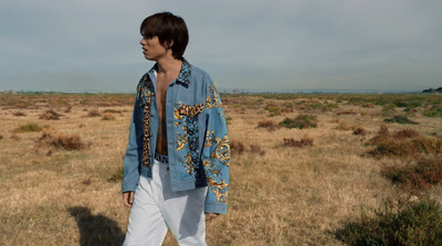 a man walking across a dry grass covered field