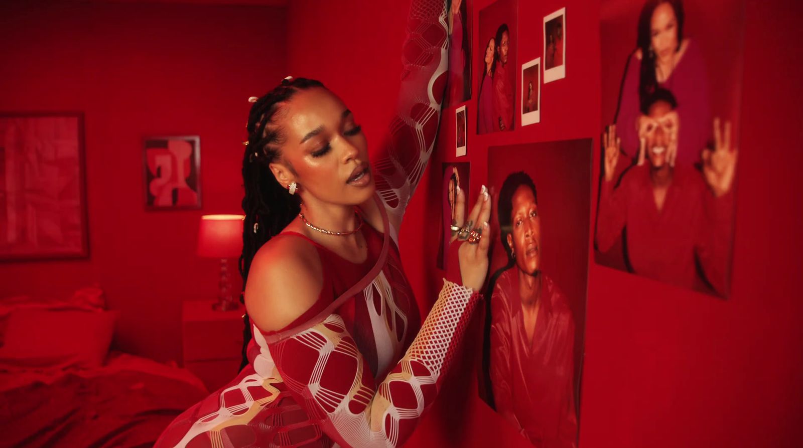 a woman standing next to a red wall with pictures on it