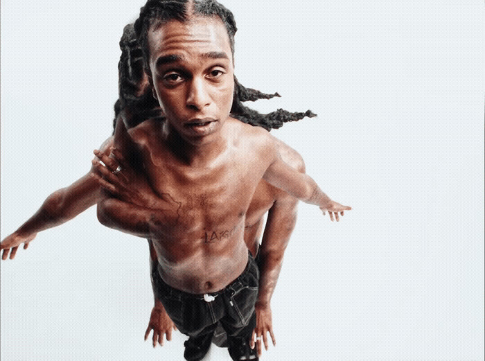 a man with dreadlocks standing in front of a white background