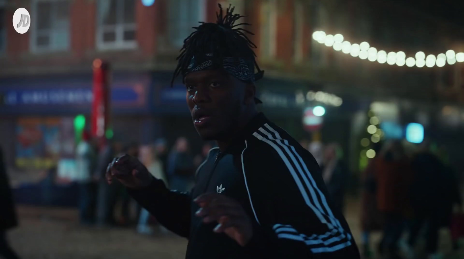 a man with dreadlocks running on a street at night