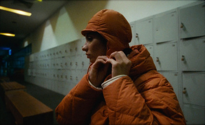 a woman in an orange jacket talking on a cell phone