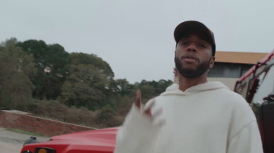 a man in a hoodie standing in front of a red truck