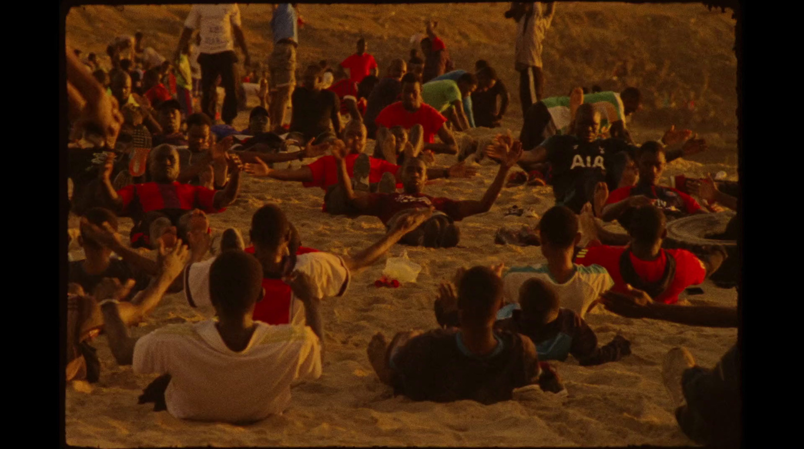 a group of people sitting on top of a sandy beach