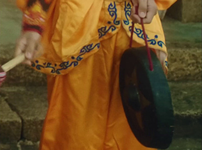 a man in a yellow outfit holding a drum