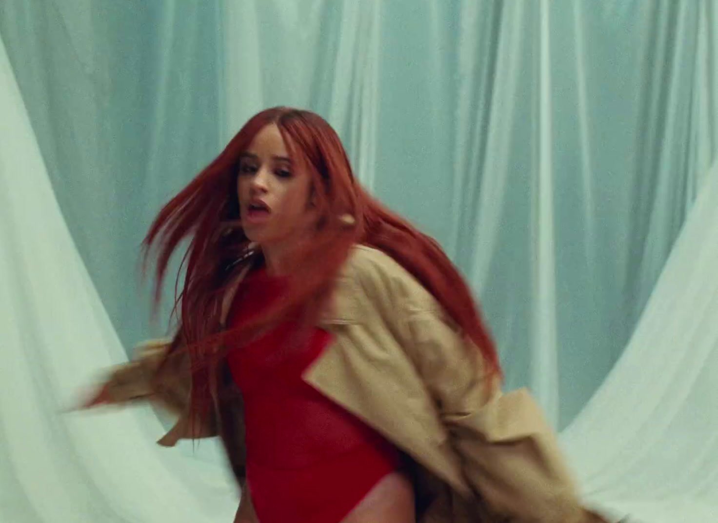 a woman with red hair is dancing in front of a curtain