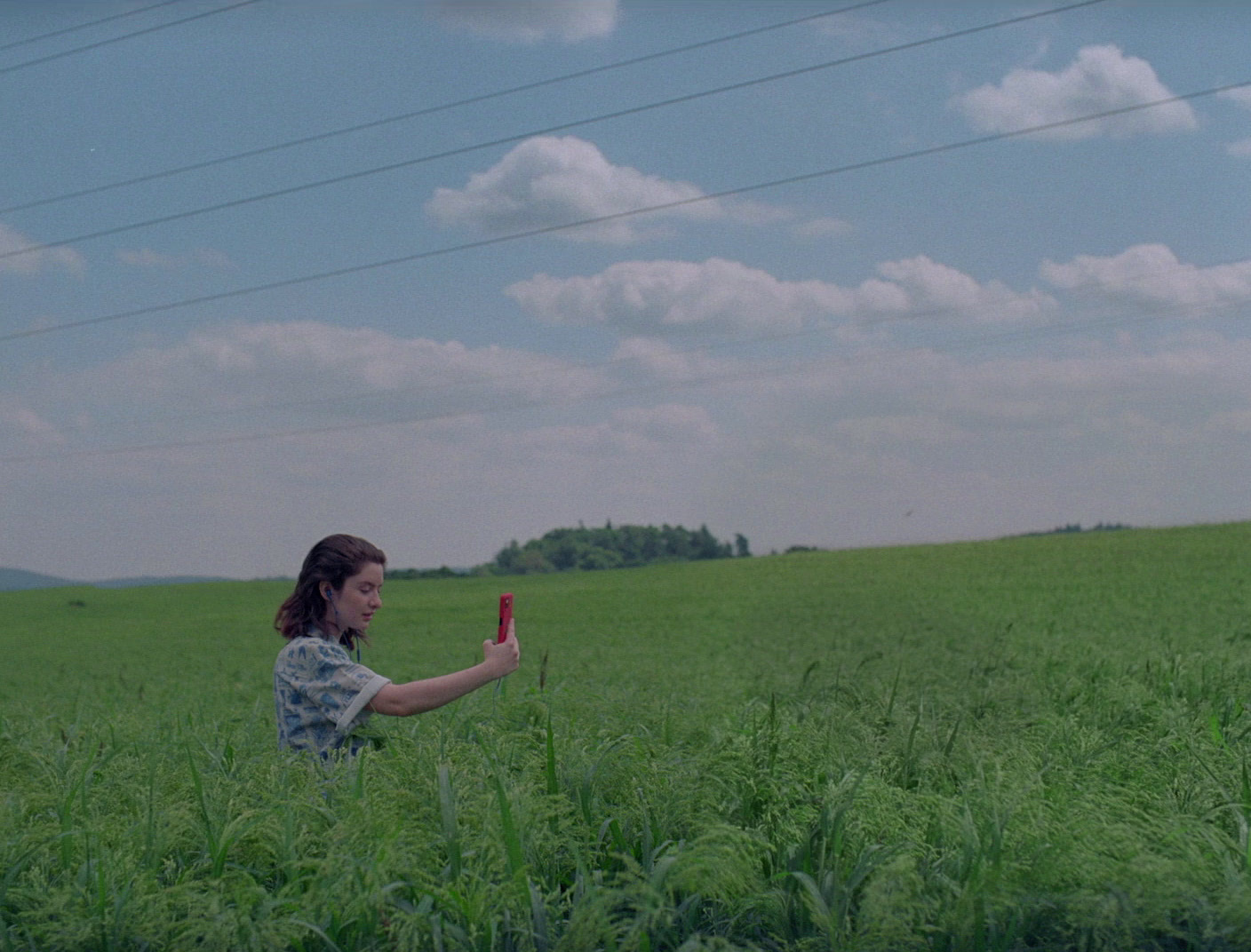 a woman standing in a field holding a red object