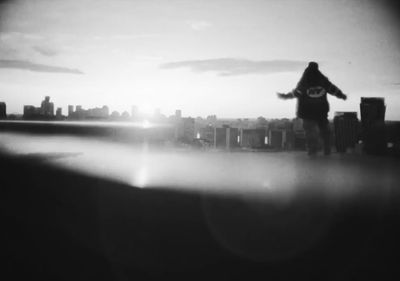 a man standing on top of a roof next to a tall building