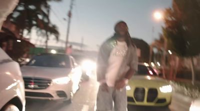 a man standing on the side of a road next to parked cars