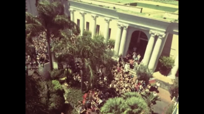 an aerial view of a crowd of people in front of a building