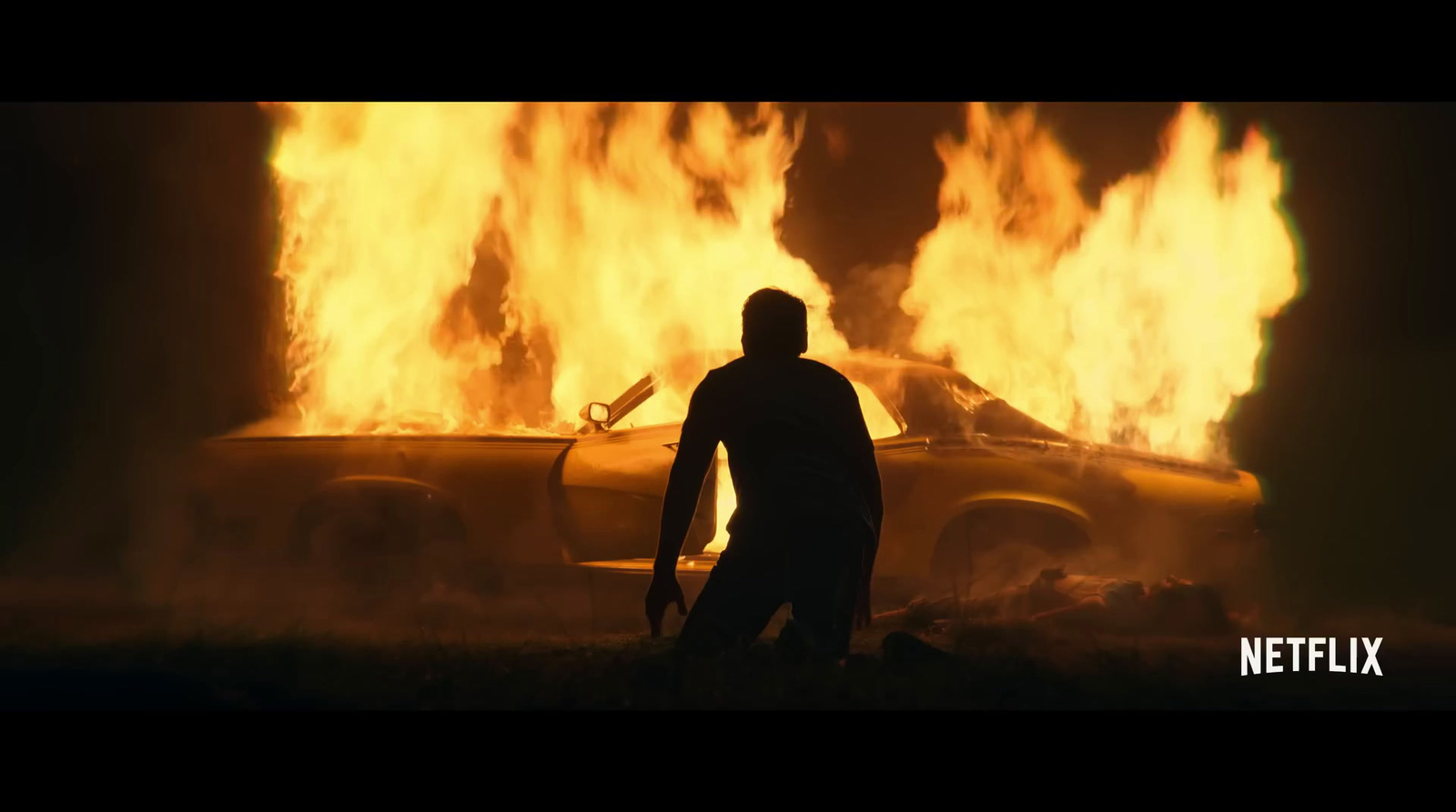 a man standing in front of a car on fire