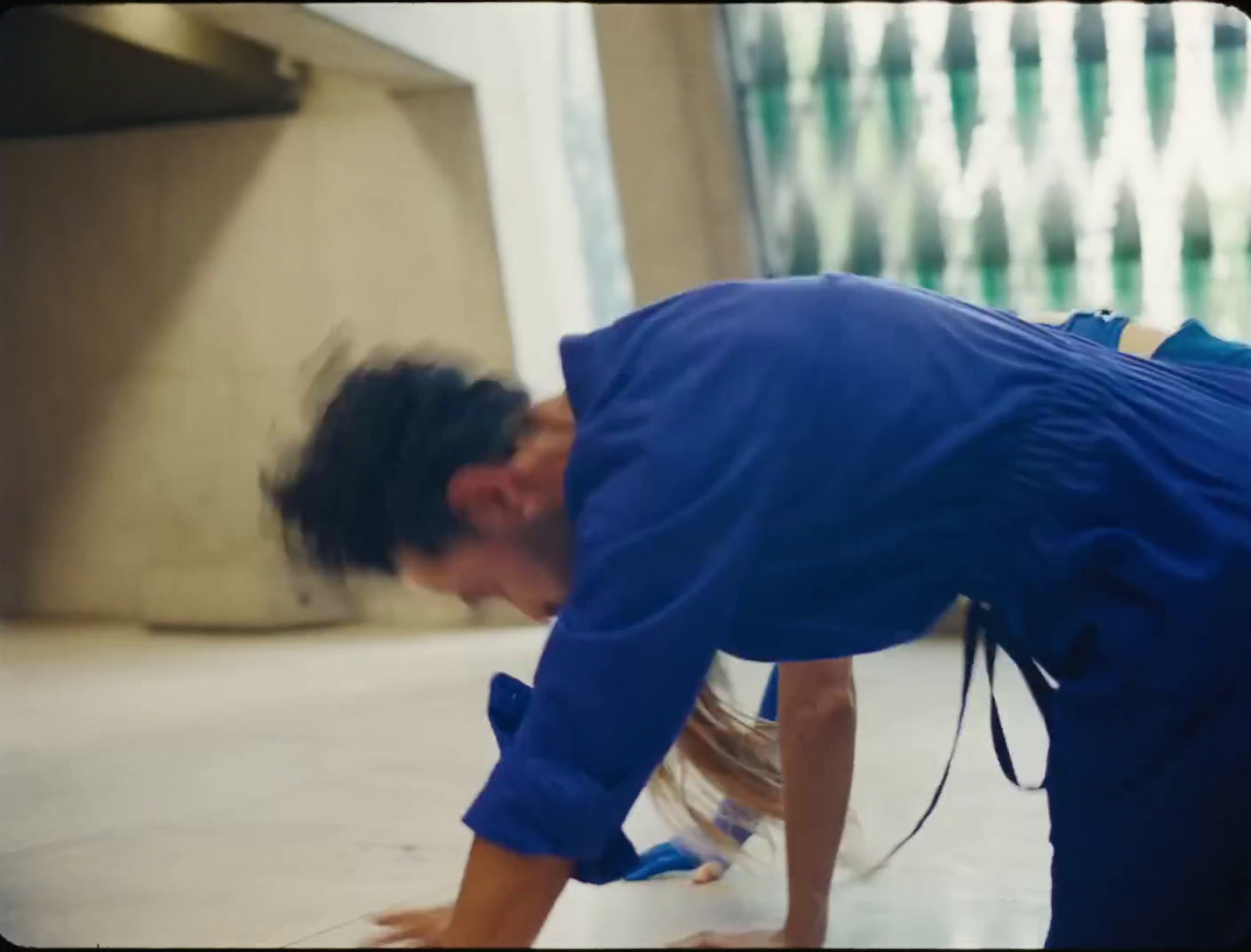 a man in a blue shirt bending over on a skateboard