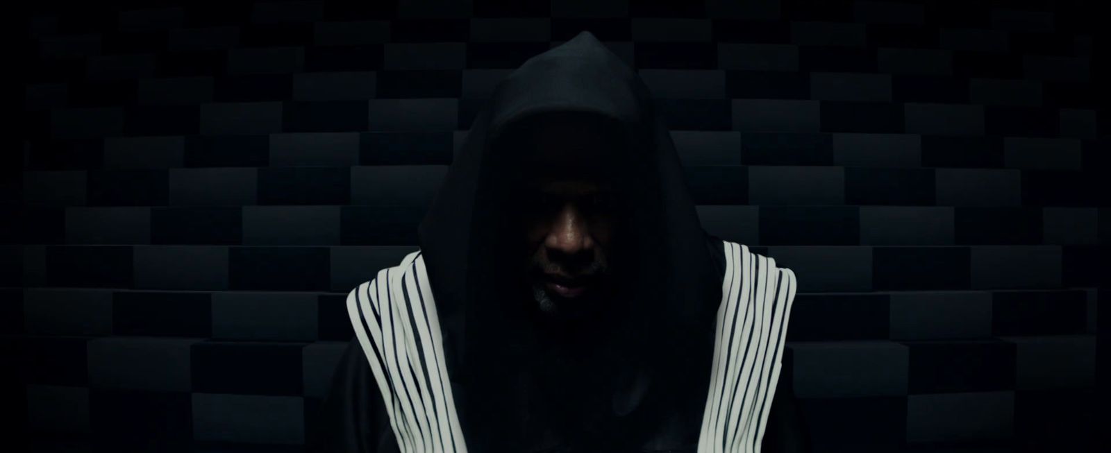 a man in a hoodie standing in a dark room