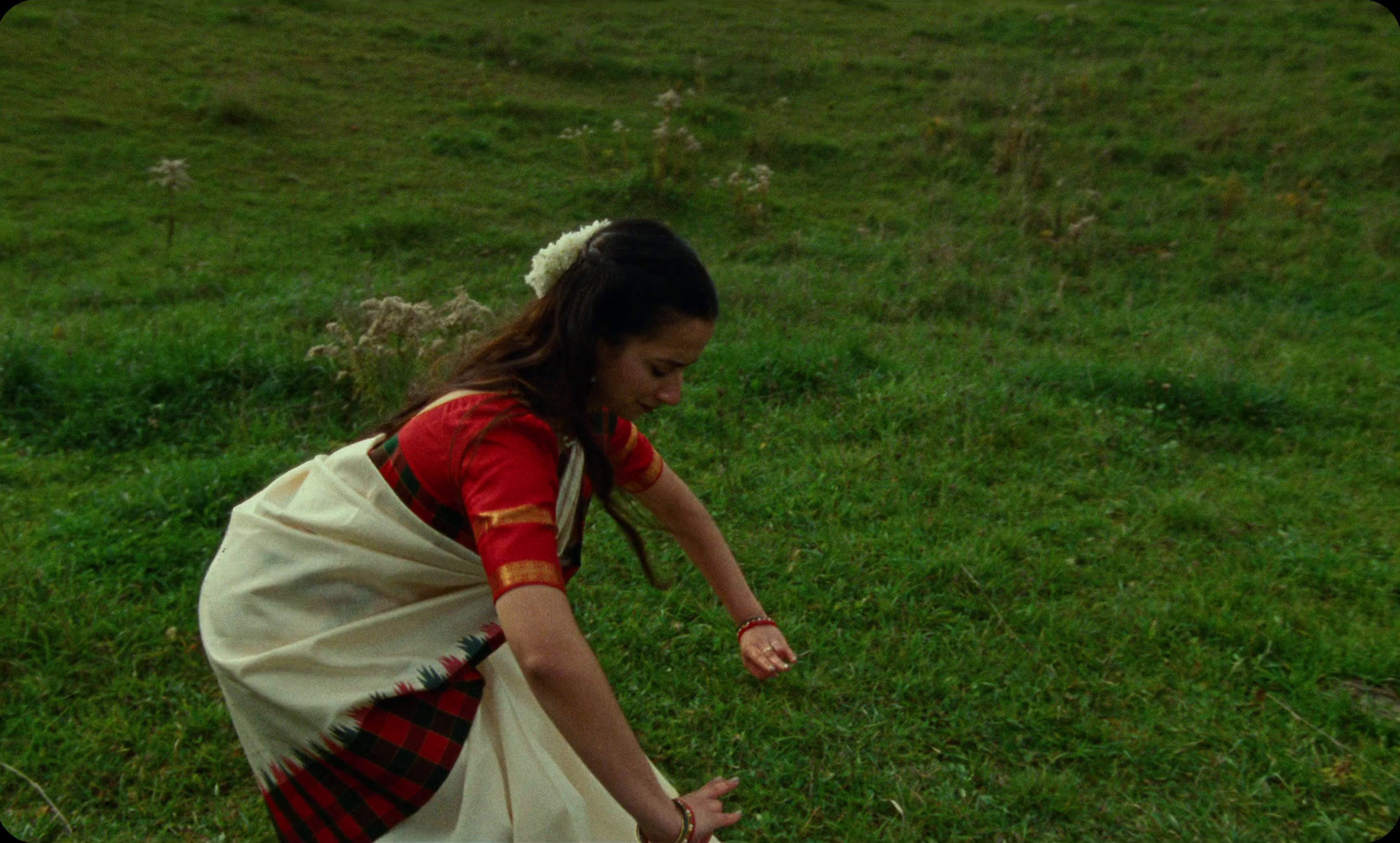 a woman in a dress reaching for a frisbee