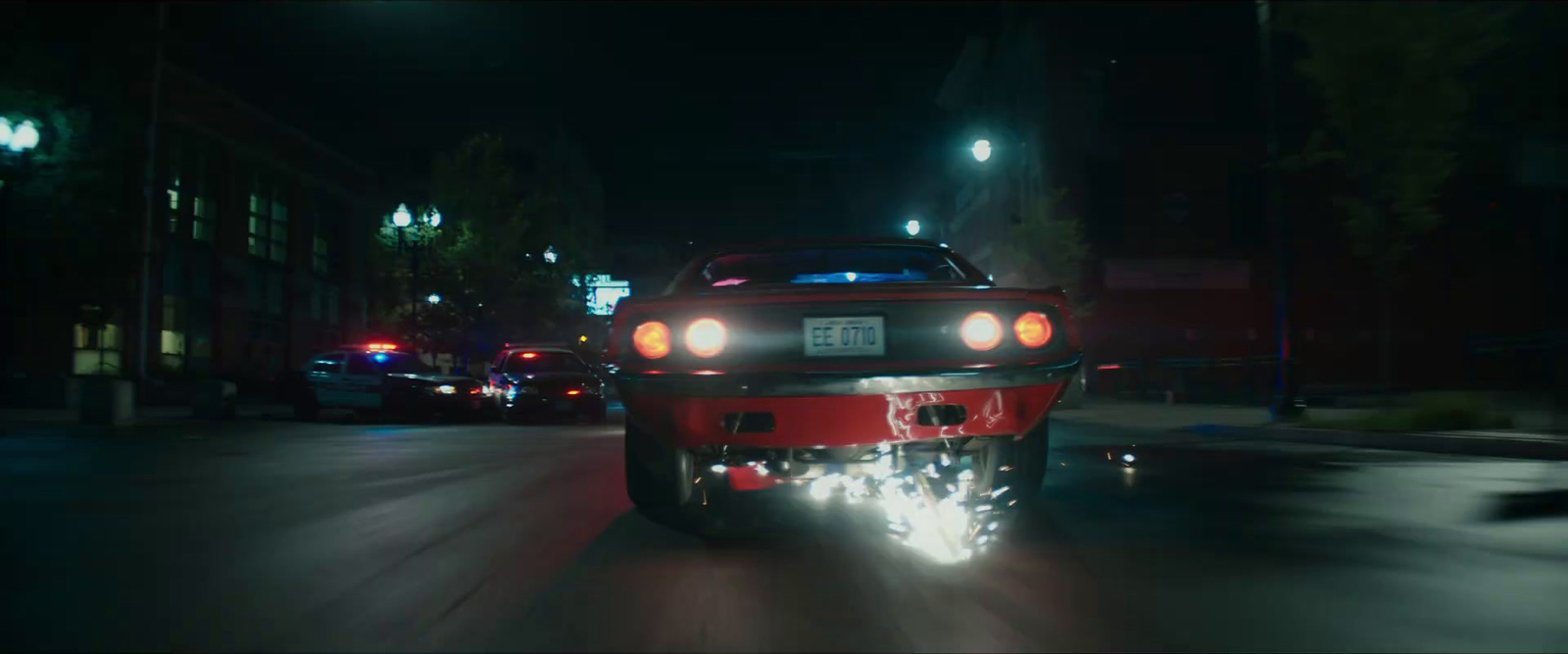 a red car driving down a street at night