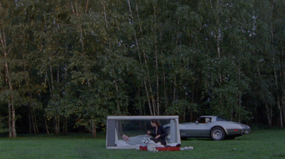 a car is parked next to a tent in the grass