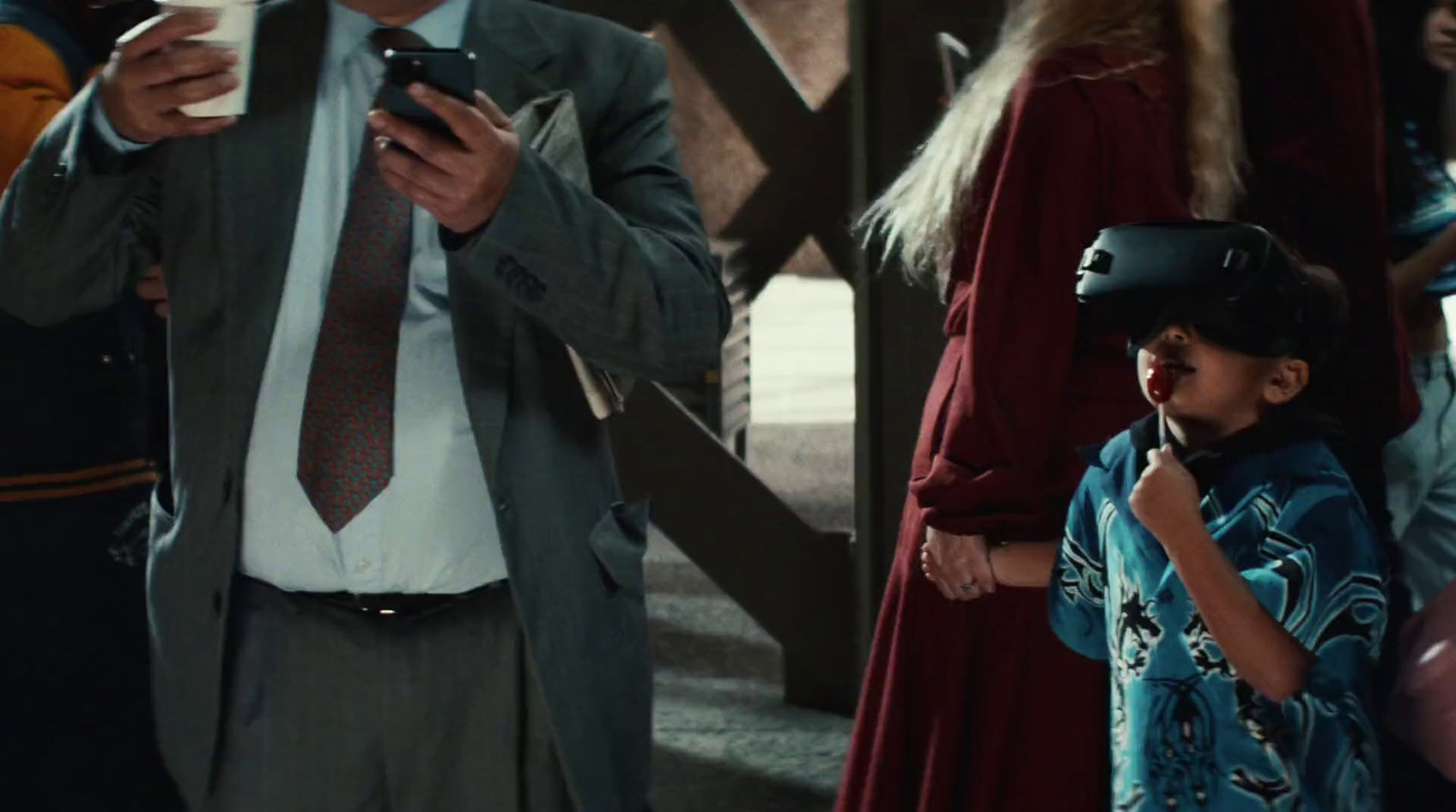 a man standing next to a little girl holding a cell phone